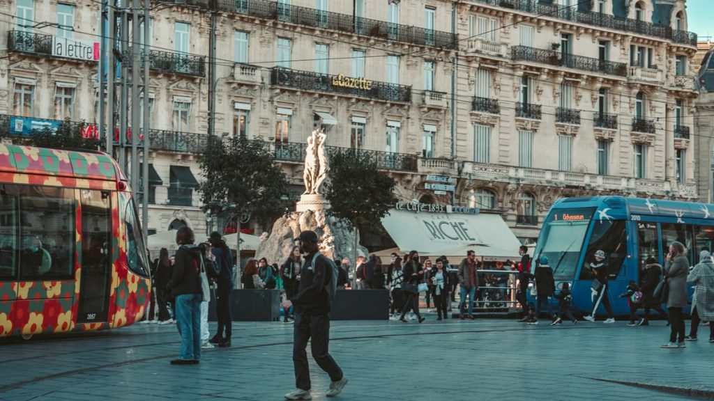 Vibrant street view in Montpellier with colorful trams and classic architecture.