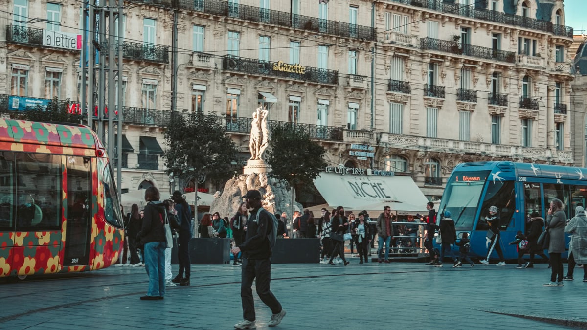 Vibrant street view in Montpellier with colorful trams and classic architecture.